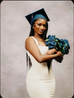 a woman wearing a graduation cap and gown holding blue roses in her hands while posing for the camera