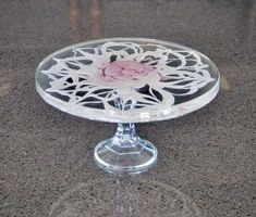 a glass cake plate with a pink flower on it