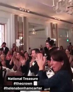 people are sitting in chairs and clapping at the national treasures awards ceremony, with one woman holding her hands up to her face