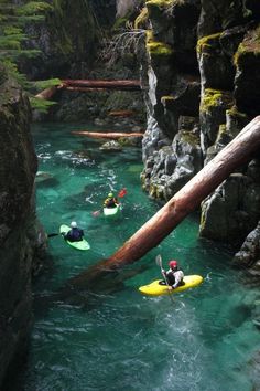 two people are paddling on their surfboards in the water next to some rocks