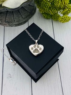 a dog's paw print is on the inside of a heart - shaped pendant