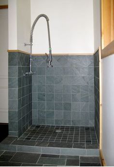 a bathroom with gray tile and wood trimmings on the walls, along with a shower head