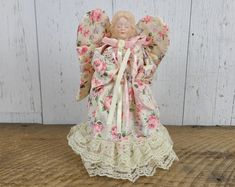 an angel figurine is sitting on a wooden table next to a white wall