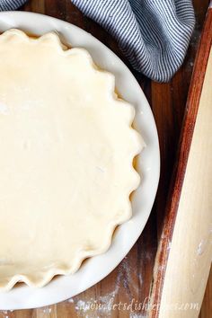 a pie crust sitting on top of a white plate next to a wooden spatula