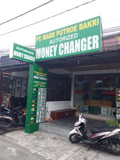 motorcycles are parked in front of a bank with money changer on the street side