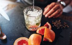 grapefruits cut in half on a cutting board next to a glass of water