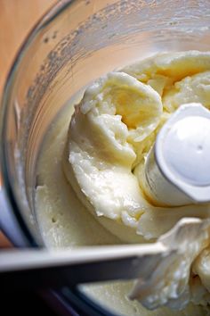 a food processor filled with bananas on top of a wooden table