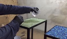 two tables with blue and green gravel on them, one being held over by someone's hand