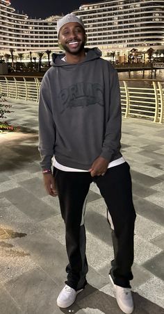 a man standing in front of a building wearing a sweatshirt and sweatpants with the word paris on it