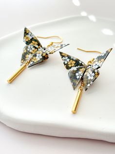 the earrings are decorated with flowers and gold sticks