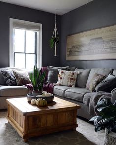 a living room filled with furniture and a large painting on the wall above it's windows