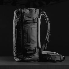 a black and white photo of a back pack with straps on the side, sitting on a table