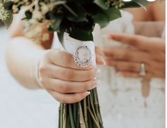 a woman holding a bouquet of flowers in her hand with the bride's wedding ring on it