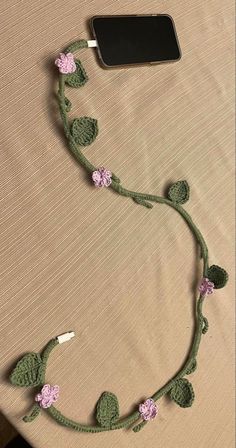 a cell phone is hooked up to a crocheted cord with flowers on it