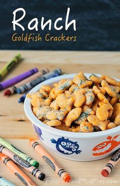 a white bowl filled with goldfish crackers next to crayons and markers