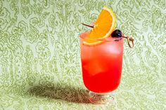 a red drink with an orange slice on the rim