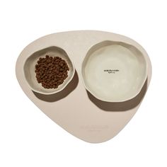 two white bowls with brown dog food in them