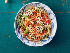 a white bowl filled with shredded carrots on top of a blue table