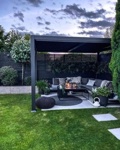 an outdoor living area with couches, tables and fire pit in the middle of it