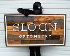 a person holding a sign that says sloan optometry