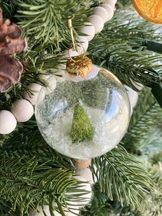 an ornament hanging from a christmas tree filled with snow and pineconis