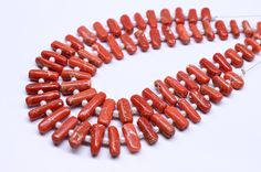 a strand of red and white beads on a white surface with an arrow in the middle