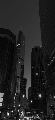 black and white photograph of city street at night with skyscrapers in the back ground