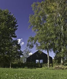 a black barn surrounded by trees and grass