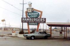 an old car parked in front of a hamburger restaurant