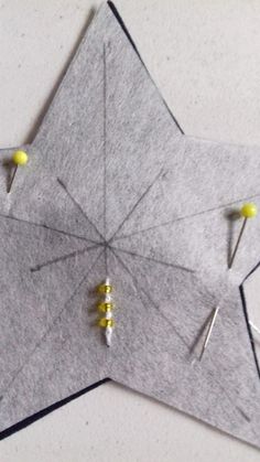 an origami star with pins stuck to it's side and two yellow pins sticking out of the middle