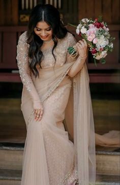 a woman in a beige sari holding flowers