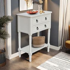 a white table with two drawers and a basket on it in front of a gray wall