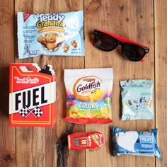 the contents of a candy bar laid out on a wooden floor next to sunglasses and other items