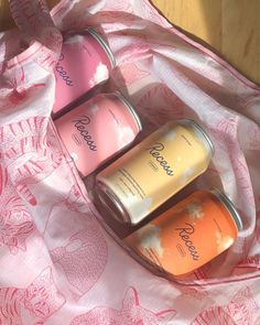 three cans of tea sitting on top of a pink blanket