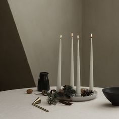 a table topped with white candles and black dishes