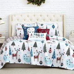 a white bed with christmas themed comforters and pillows in front of a brick wall