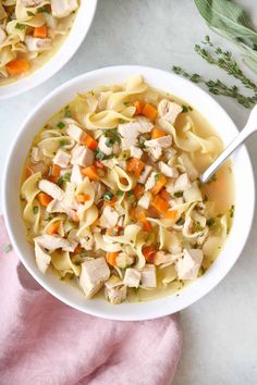 two bowls filled with chicken noodle soup on top of a table