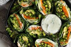 a platter filled with veggies covered in ranch dressing next to a bowl of dip