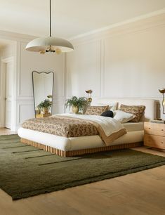 a bedroom with a bed, dresser and mirror in the corner next to a green rug