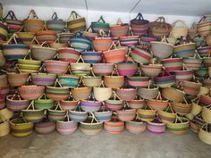 many baskets are stacked on top of each other in different colors and sizes, including straw