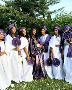 a group of women standing next to each other in white dresses and purple head coverings