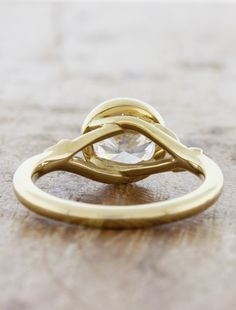 a yellow gold ring with a diamond in the center on top of a wooden table