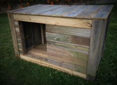 a dog house made out of pallet wood in the grass with its door open