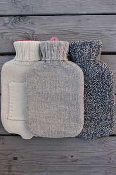 three knitted hot water bottles sitting on top of a wooden table