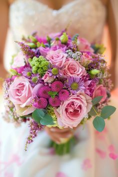 a bridal holding a bouquet of pink and purple flowers