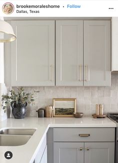 a kitchen with gray cabinets and white counter tops, gold trim on the cabinet doors