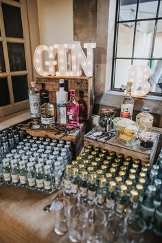 bottles of gin are on display in front of a sign that reads gin bar and is surrounded by empty wine glasses