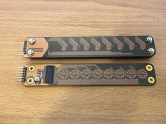 two black and gold guitar pickups sitting on top of a wooden table