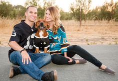 a man and woman sitting on the ground with their dog