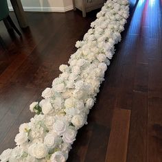 a long line of white flowers sitting on top of a wooden floor